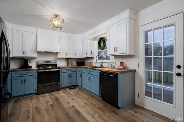 kitchen with butcher block counters, a sink, blue cabinets, and black appliances