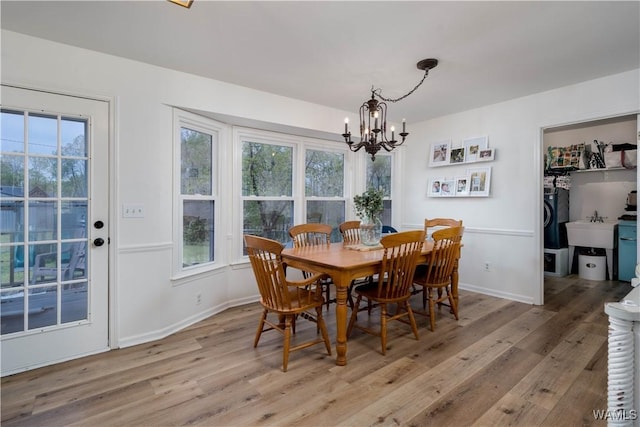 dining space featuring light wood-style flooring, plenty of natural light, and a notable chandelier