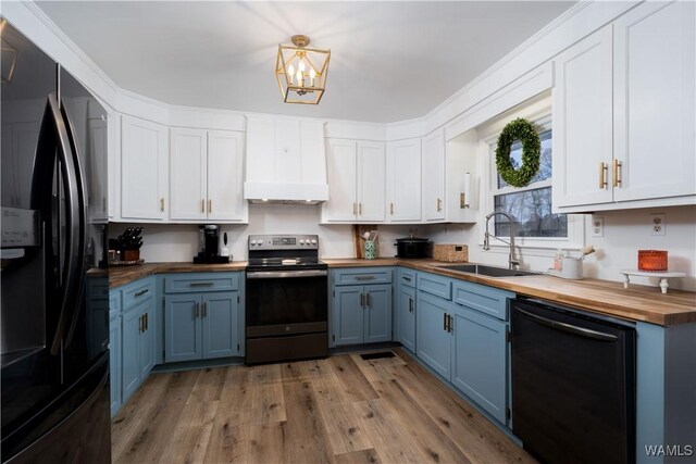 kitchen featuring wooden counters, blue cabinets, a sink, and black appliances