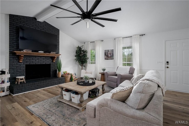living room with a fireplace, vaulted ceiling with beams, wood finished floors, and a ceiling fan