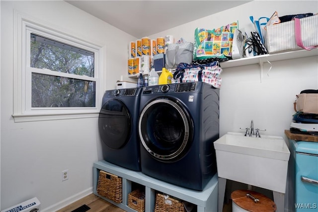 washroom featuring baseboards, washing machine and dryer, laundry area, a sink, and wood finished floors