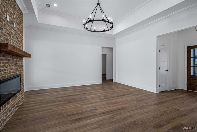 unfurnished living room featuring crown molding, dark wood-type flooring, a fireplace, and a tray ceiling