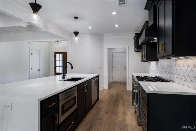 kitchen with pendant lighting, sink, stainless steel appliances, and wall chimney exhaust hood