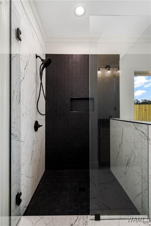 bathroom with ornamental molding and a tile shower