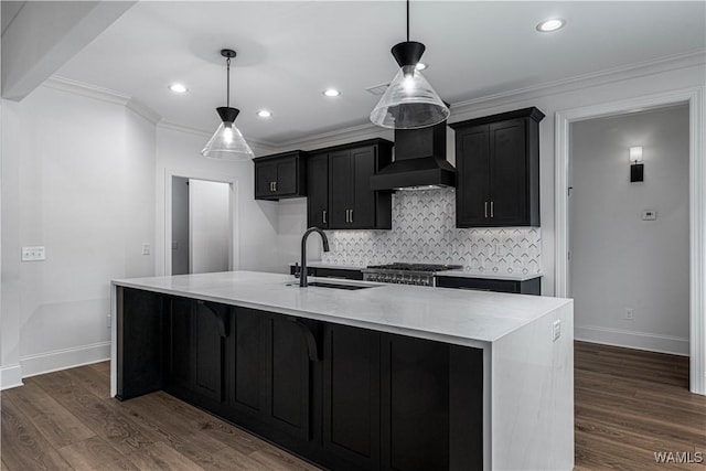 kitchen with pendant lighting, sink, custom range hood, and a center island with sink