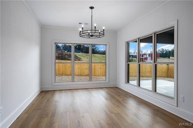 unfurnished dining area featuring crown molding, an inviting chandelier, and hardwood / wood-style floors