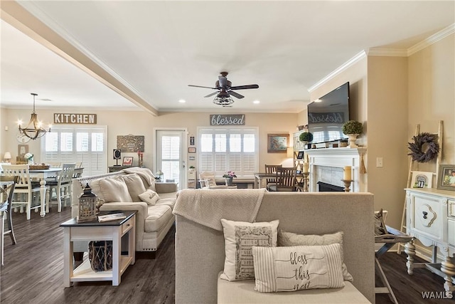 living room featuring dark wood-style floors, a fireplace, recessed lighting, ornamental molding, and ceiling fan with notable chandelier