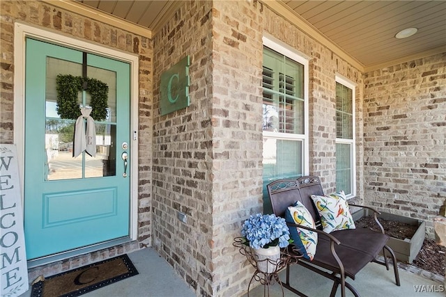 doorway to property featuring covered porch and brick siding