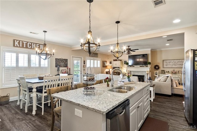 kitchen featuring appliances with stainless steel finishes, a fireplace, a sink, and visible vents