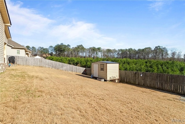 view of yard with a fenced backyard, a storage unit, and an outdoor structure