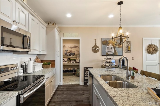 kitchen featuring dark wood finished floors, crown molding, backsplash, appliances with stainless steel finishes, and a sink