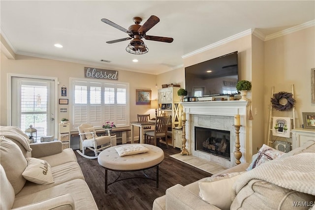 living area featuring dark wood-style floors, recessed lighting, a tiled fireplace, ornamental molding, and ceiling fan