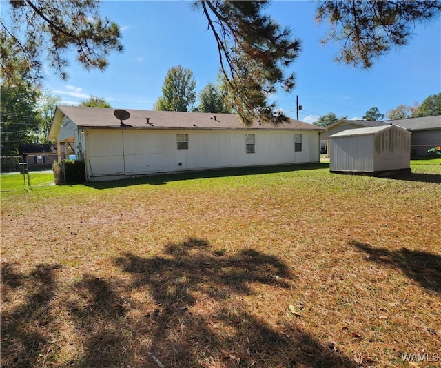 rear view of house featuring a yard and a storage unit