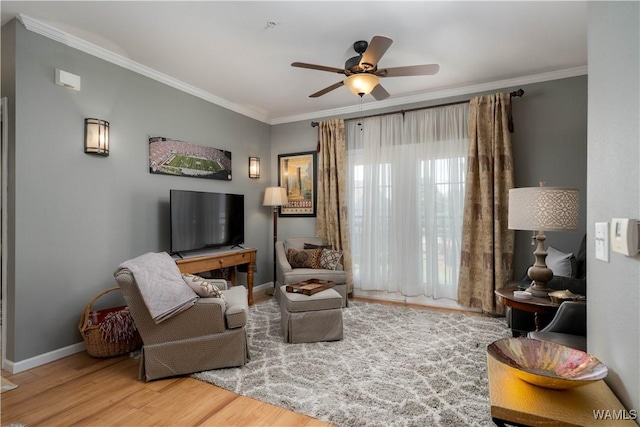 sitting room with ceiling fan, baseboards, ornamental molding, and wood finished floors