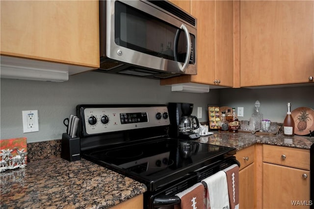 kitchen with dark stone counters and appliances with stainless steel finishes