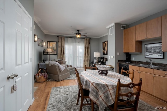 dining area featuring crown molding, a ceiling fan, visible vents, and light wood-type flooring