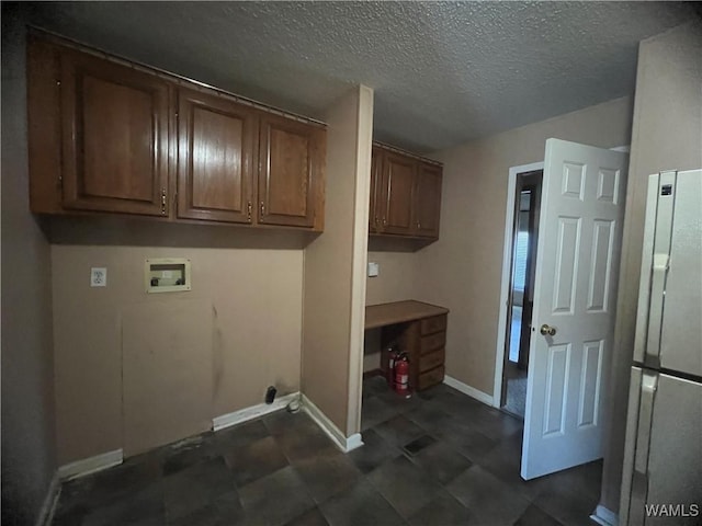 laundry area featuring baseboards, cabinet space, a textured ceiling, and hookup for a washing machine