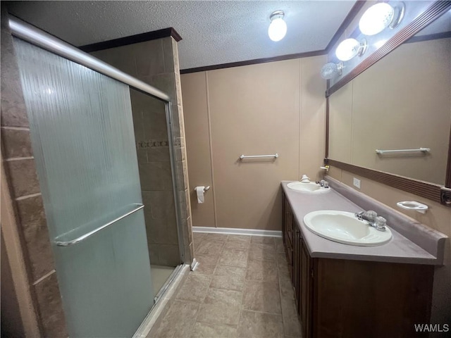full bath with double vanity, a sink, a textured ceiling, and a shower stall