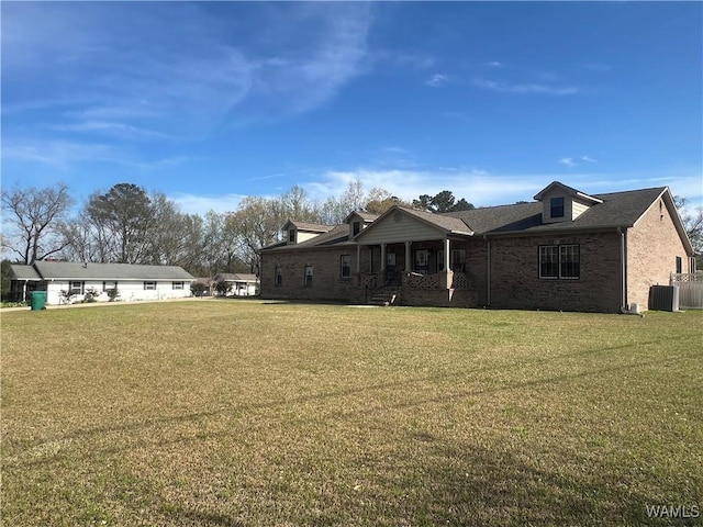exterior space with covered porch, roof with shingles, cooling unit, brick siding, and a lawn