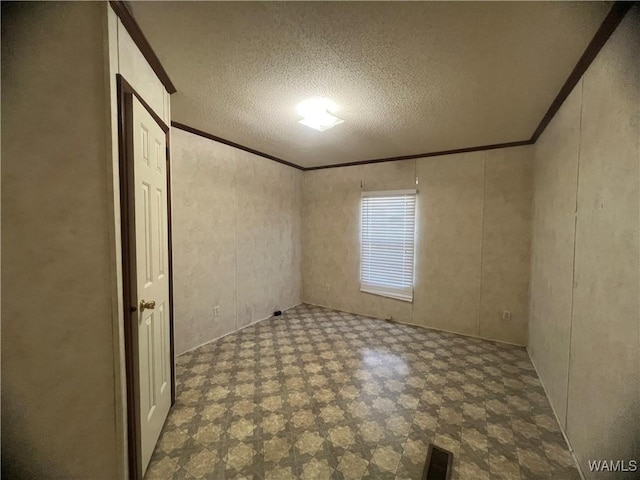 interior space with a textured ceiling, ornamental molding, visible vents, and tile patterned floors