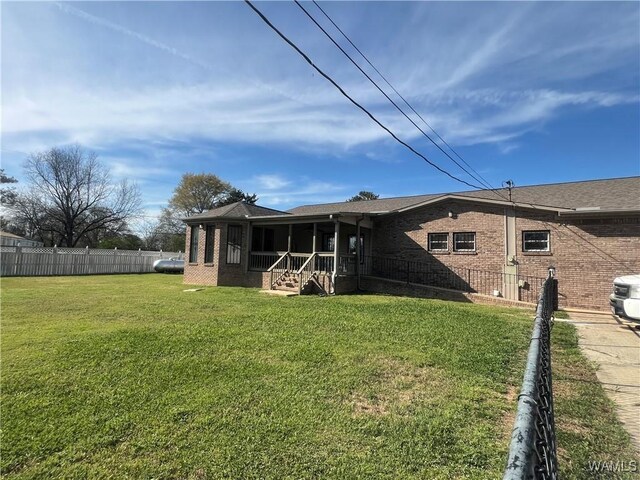 rear view of property with brick siding, fence, and a yard