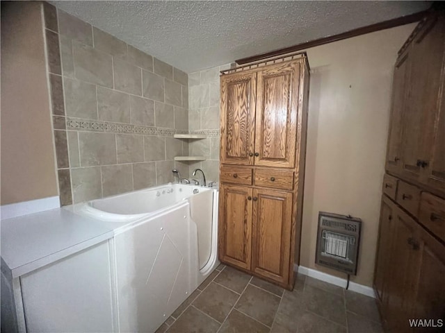 laundry room with a textured ceiling, cabinet space, heating unit, and dark tile patterned floors