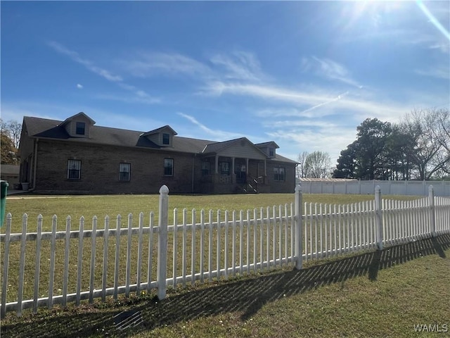 view of front facade with brick siding, fence private yard, and a front lawn