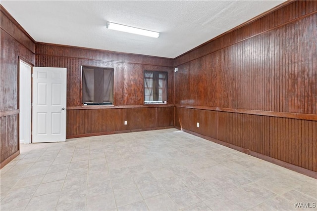 empty room with wooden walls and a textured ceiling