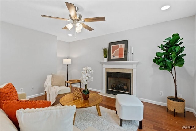 living area featuring a fireplace with flush hearth, baseboards, wood finished floors, and recessed lighting