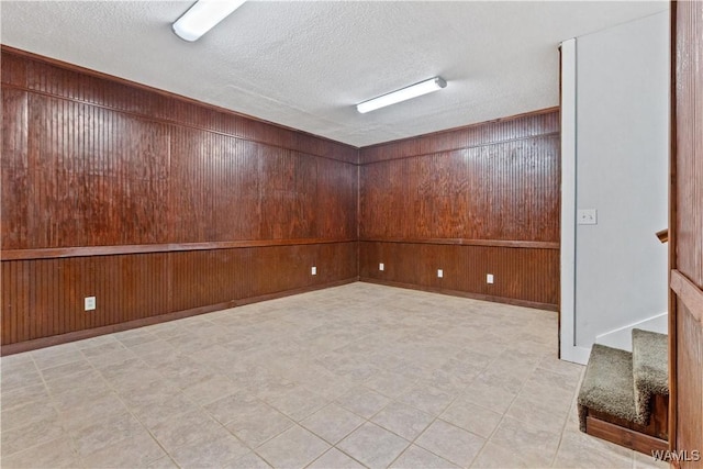 empty room featuring a textured ceiling and wood walls