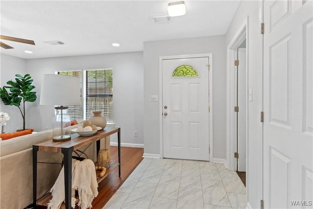 foyer with a ceiling fan, marble finish floor, visible vents, and baseboards