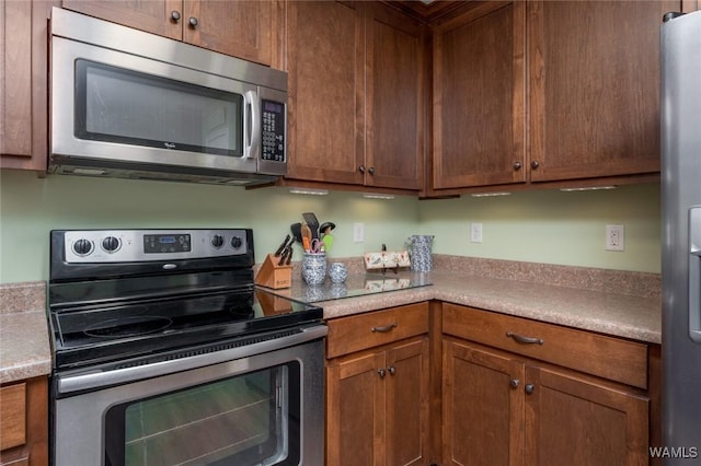 kitchen with light countertops, appliances with stainless steel finishes, and brown cabinets