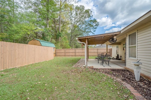 view of yard with a storage shed, ceiling fan, a fenced backyard, and a patio