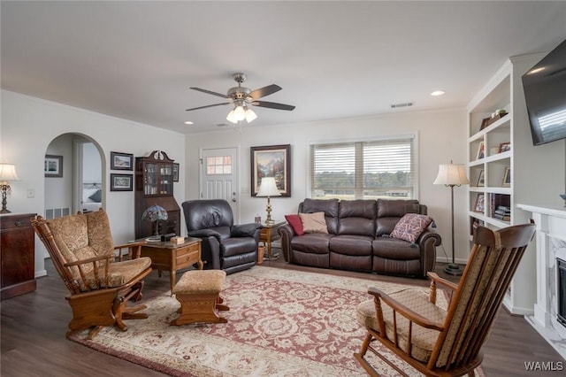 living room with a ceiling fan, arched walkways, dark wood-style flooring, and a high end fireplace