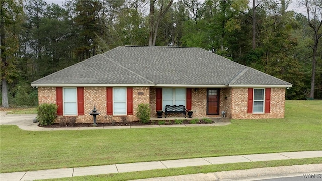 ranch-style home with roof with shingles, a front lawn, and brick siding