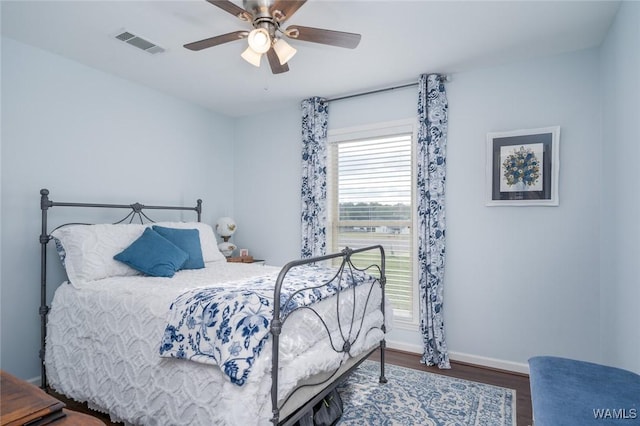 bedroom featuring dark wood-style floors, visible vents, ceiling fan, and baseboards