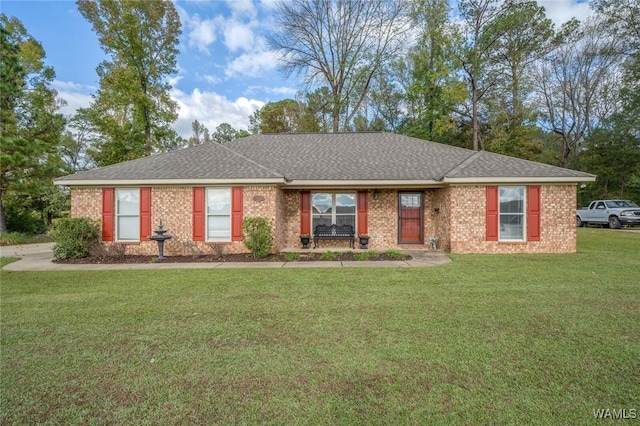 single story home featuring a shingled roof, a front yard, and brick siding