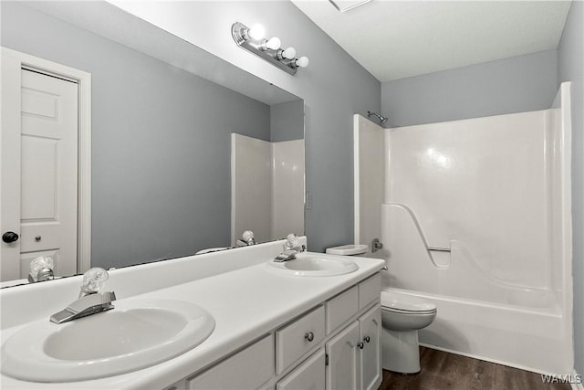 bathroom with wood finished floors, shower / washtub combination, a sink, and toilet