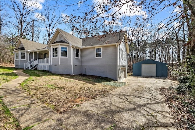 view of front facade featuring an outbuilding, driveway, covered porch, and a detached garage