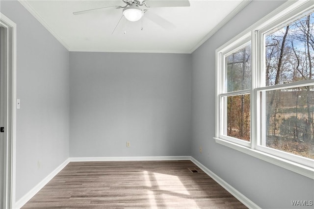 unfurnished room featuring ornamental molding, baseboards, and wood finished floors