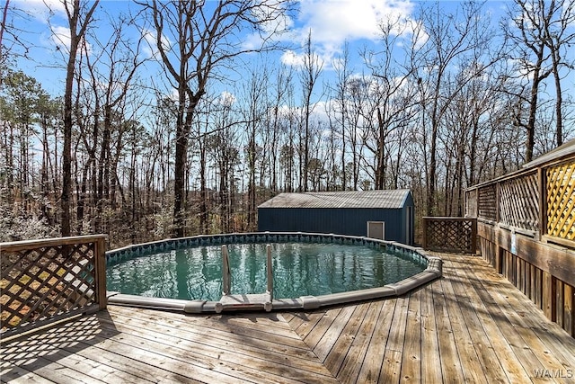 pool featuring a wooden deck, a shed, and an outdoor structure