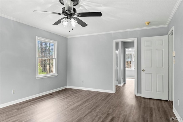 empty room featuring ornamental molding, dark wood-type flooring, a ceiling fan, and baseboards