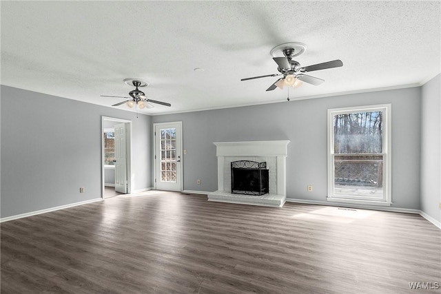 unfurnished living room featuring ceiling fan, a fireplace, wood finished floors, and baseboards