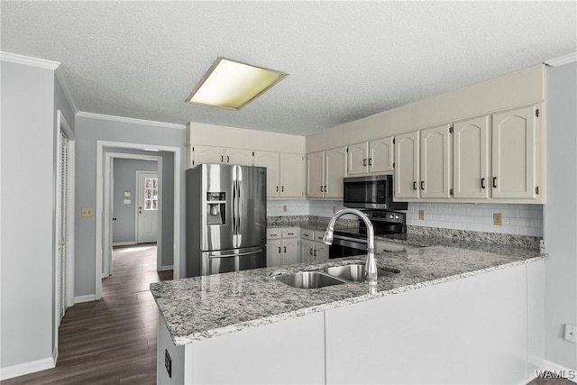 kitchen with light stone counters, stainless steel appliances, a peninsula, a sink, and backsplash