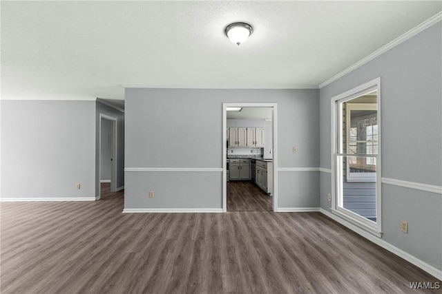 unfurnished room with dark wood-type flooring, crown molding, a textured ceiling, and baseboards