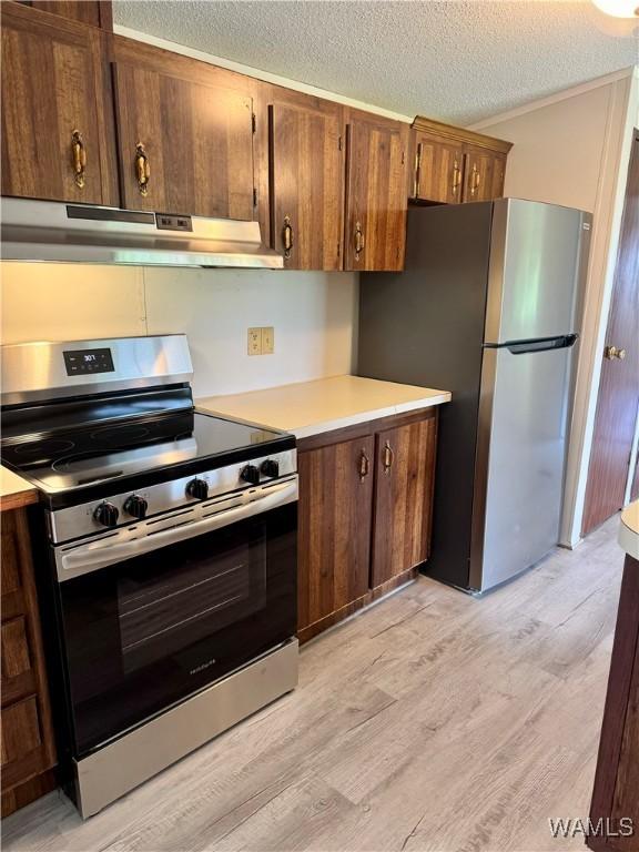 4247 W Ashby Rd, Brierfield, AL 35035 - kitchen featuring appliances with stainless steel finishes, under cabinet range hood, light countertops, light wood finished floors, and a textured ceiling