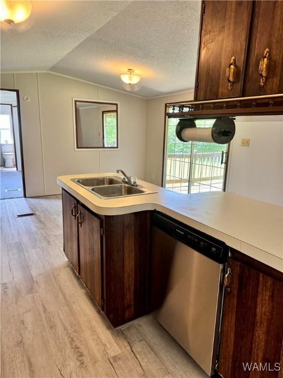 4247 W Ashby Rd, Brierfield, AL 35035 - kitchen with stainless steel dishwasher, light wood-type flooring, dark brown cabinets, vaulted ceiling, and light countertops