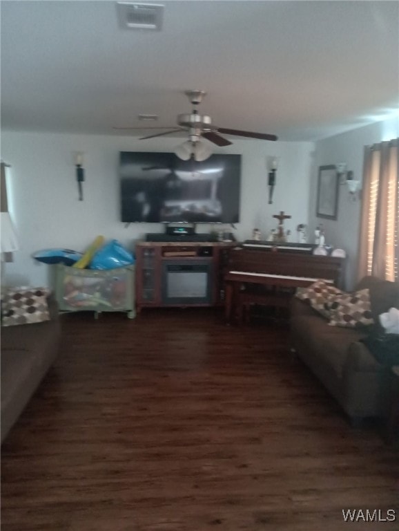 living area featuring dark wood-type flooring, visible vents, and a ceiling fan