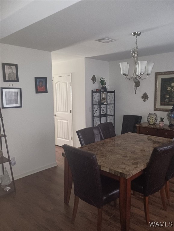 dining space featuring dark wood-style flooring, visible vents, a notable chandelier, and baseboards