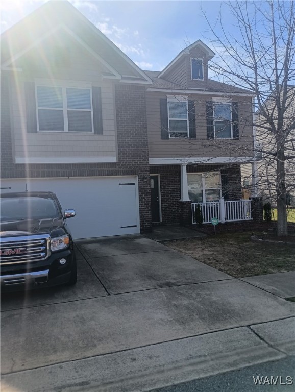 view of front of property with driveway, an attached garage, a porch, and brick siding